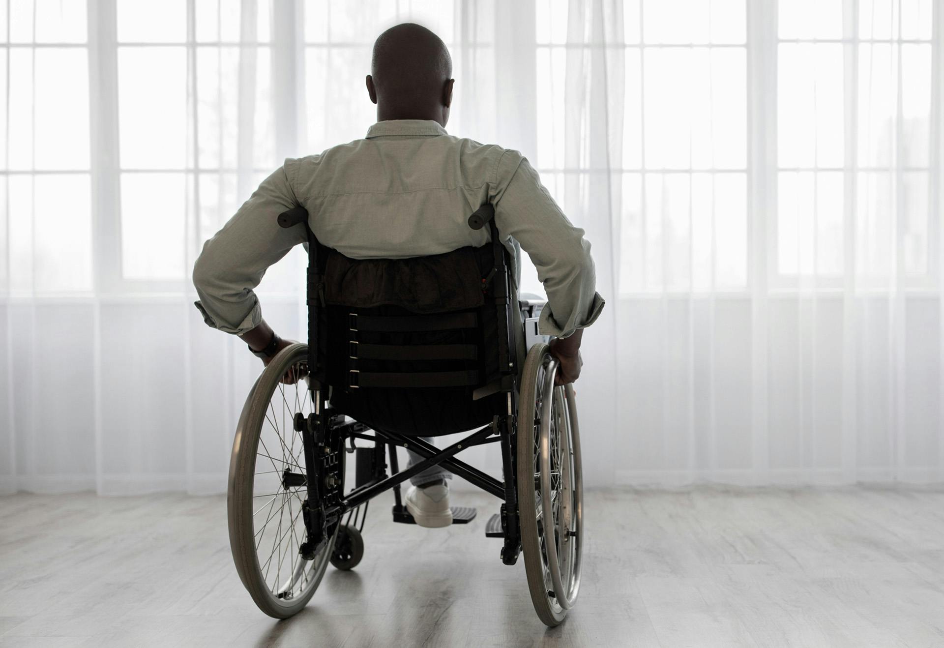 Man in a wheelchair looking out the window.