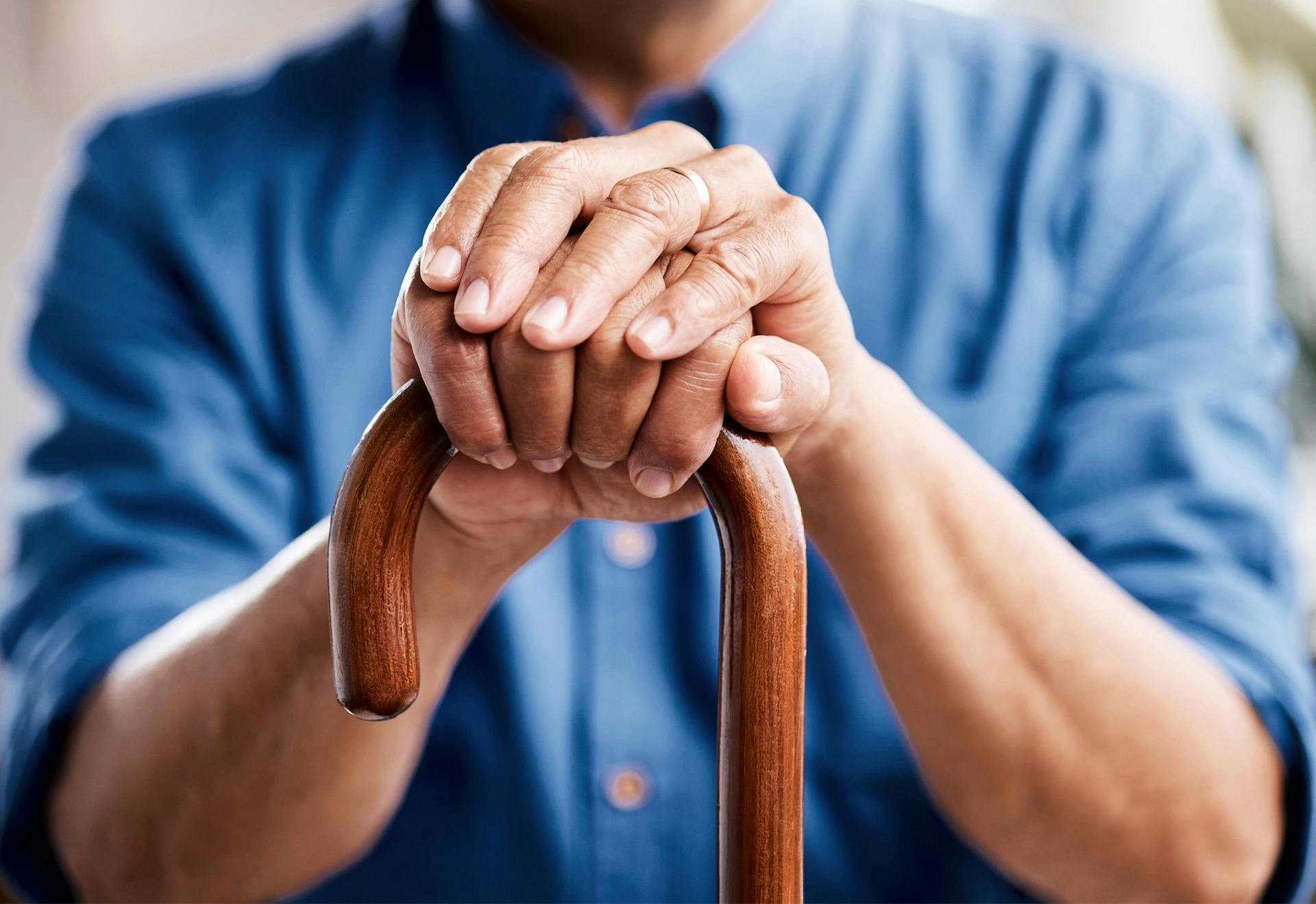 Man's hands resting on a cane.