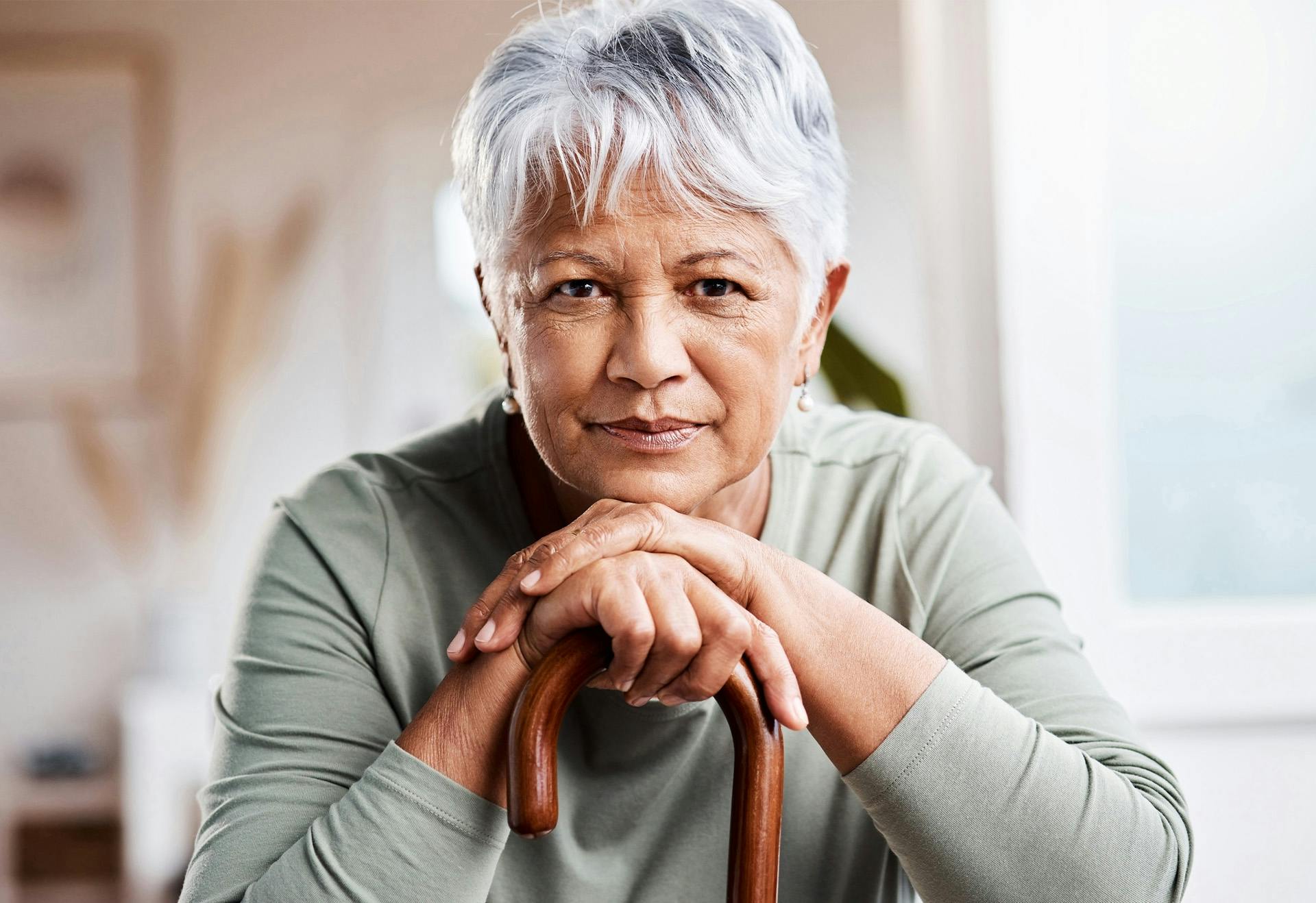 Elderly woman resting her chin on her cane.