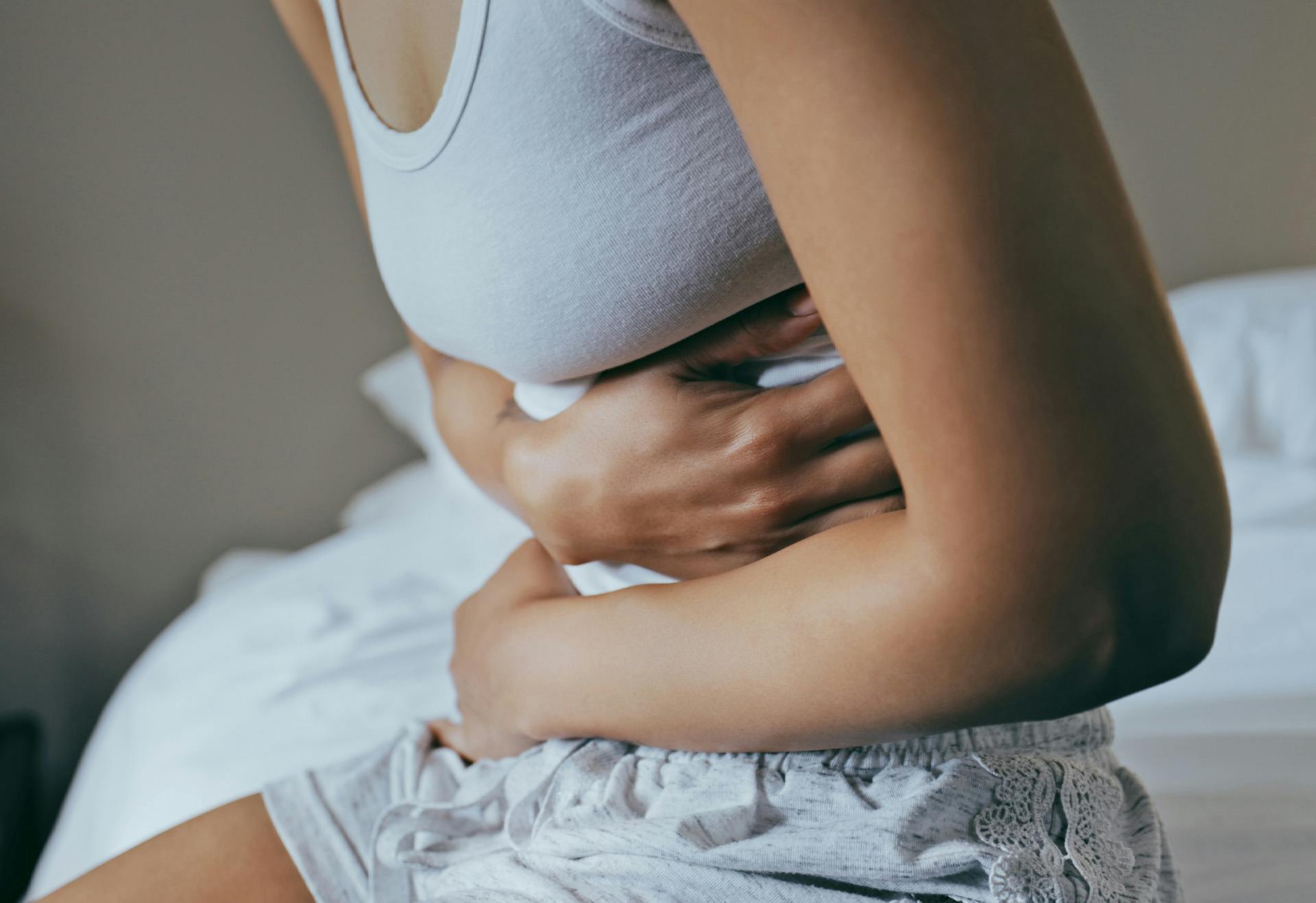 Woman sitting in bed holding her stomach