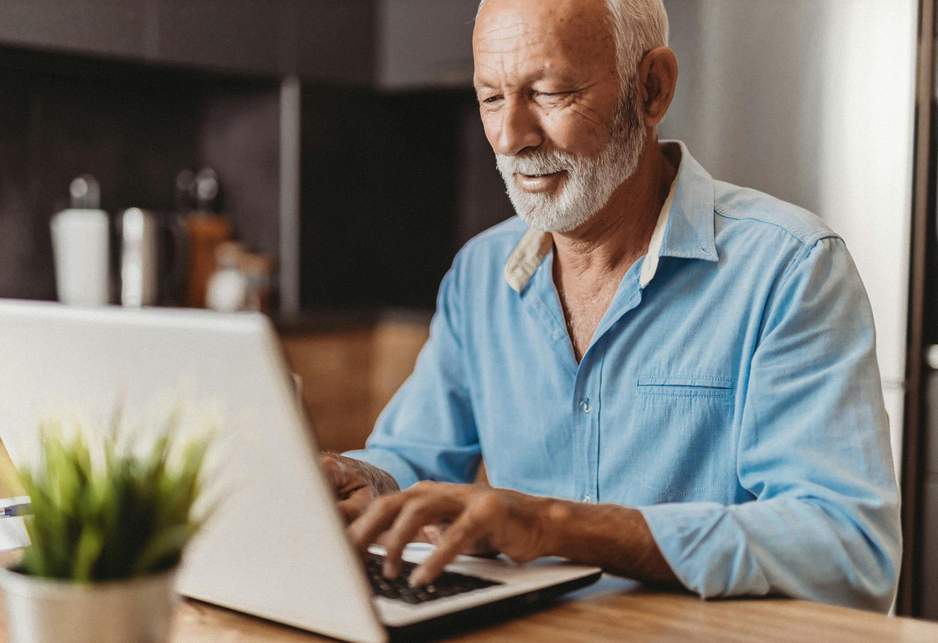 Elderly man typing on a computer.