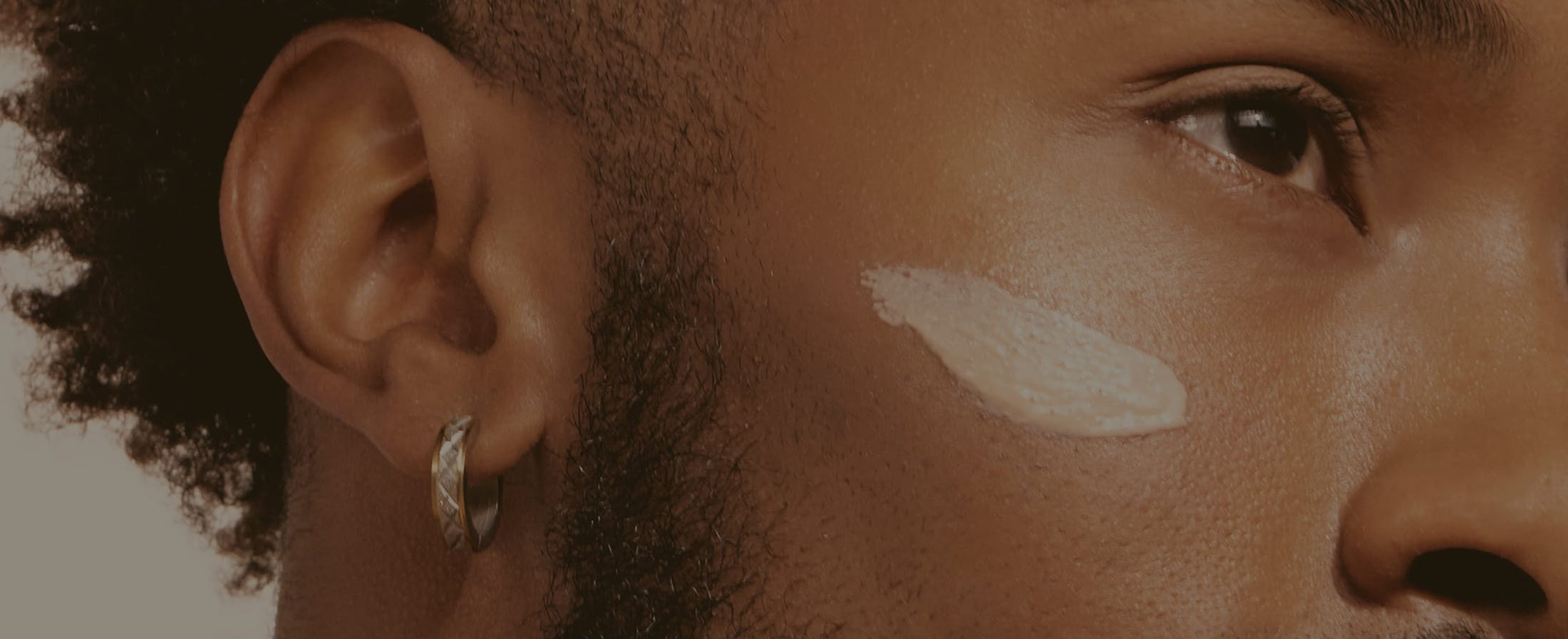 there is a close up of a man's cheek with some cosmetic cream on it