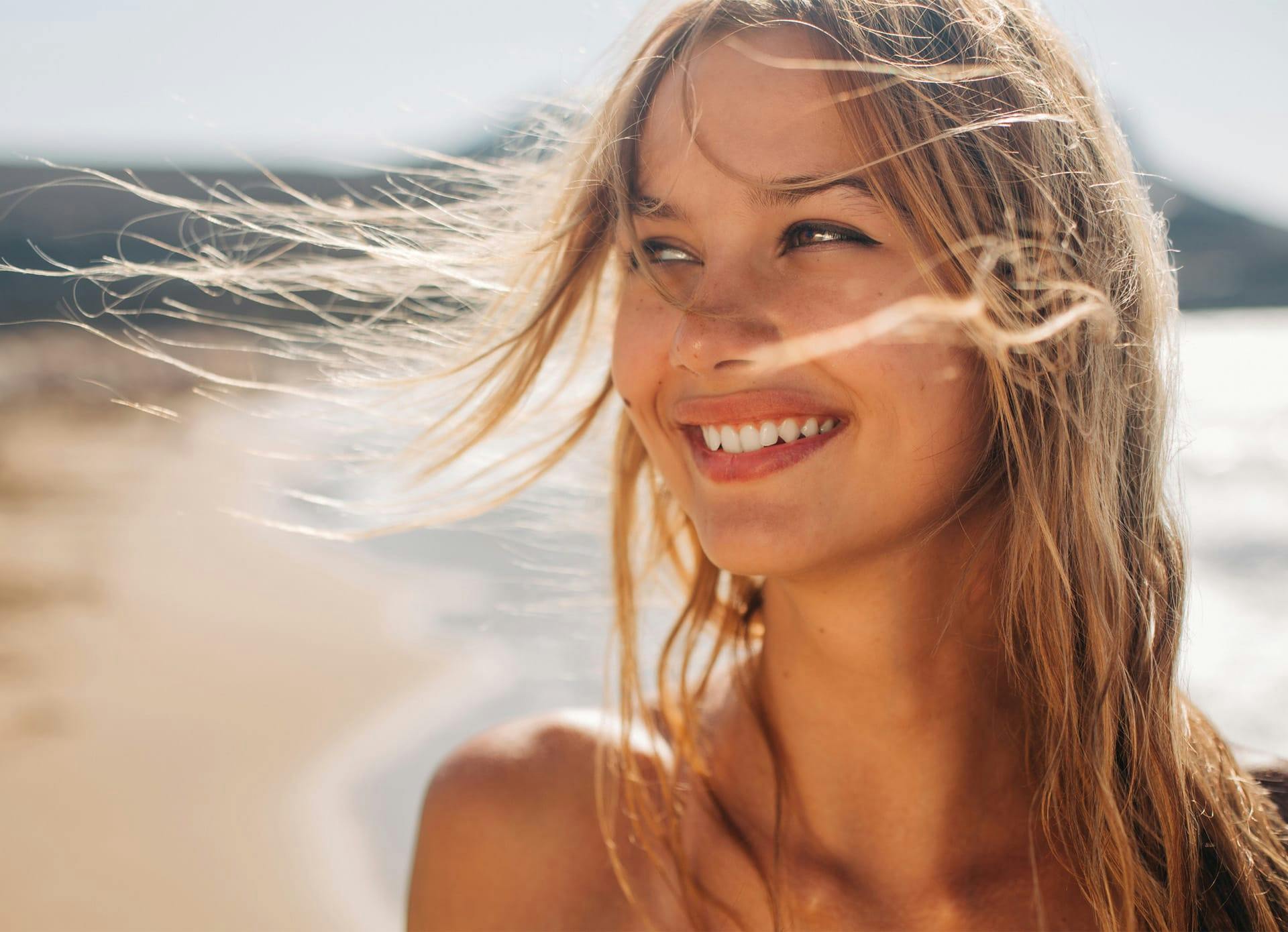 Woman Smiling at a Beach with Great Skin