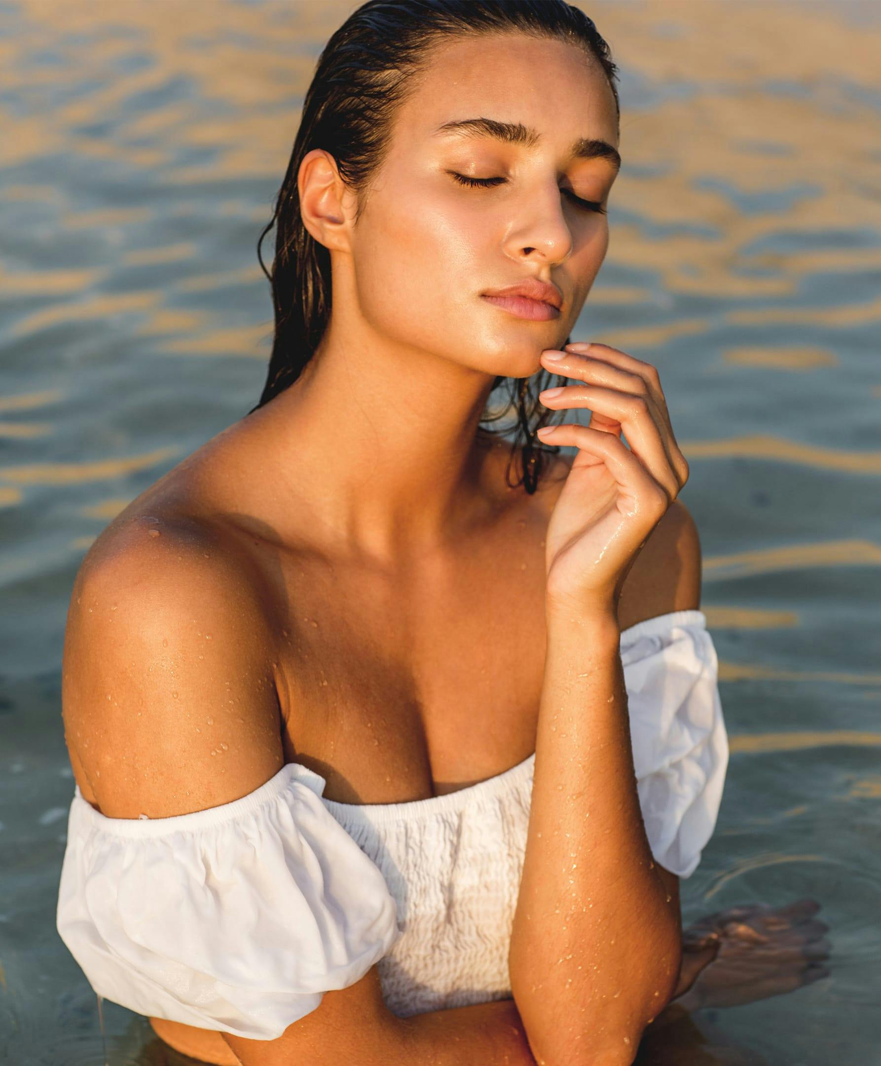 there is a woman in white strapless top in water with eyes closed
