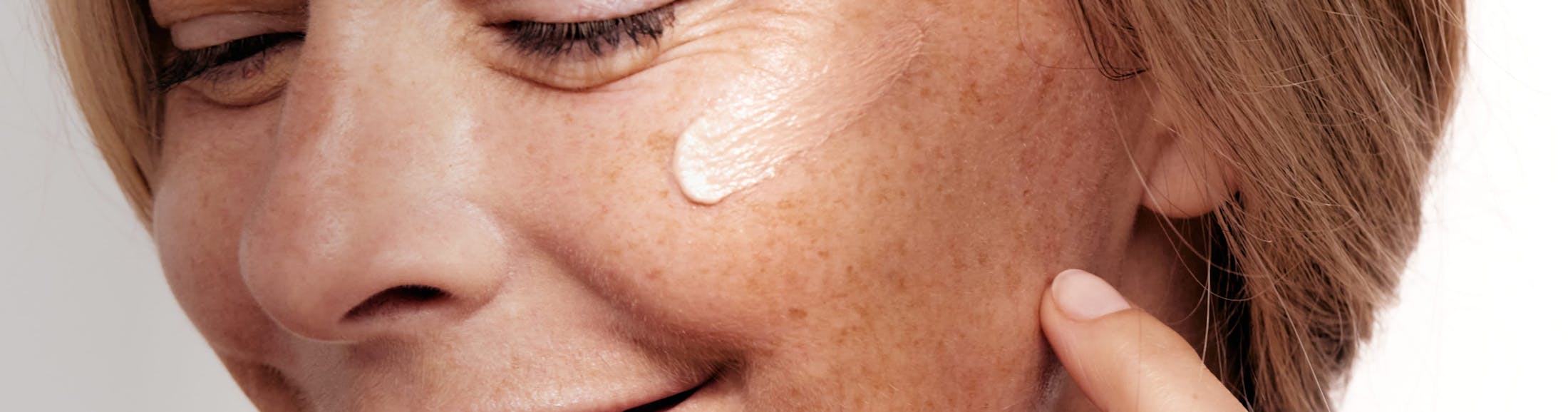 there is a close up of a woman's cheek with cosmetic cream on it