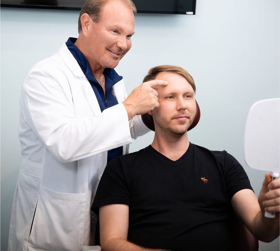 Doctor Young indicating patient's forehead in mirror