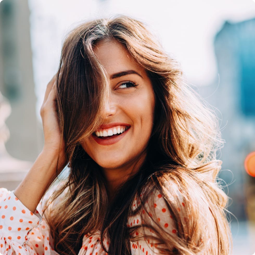 Woman smiling, with a hand to her head