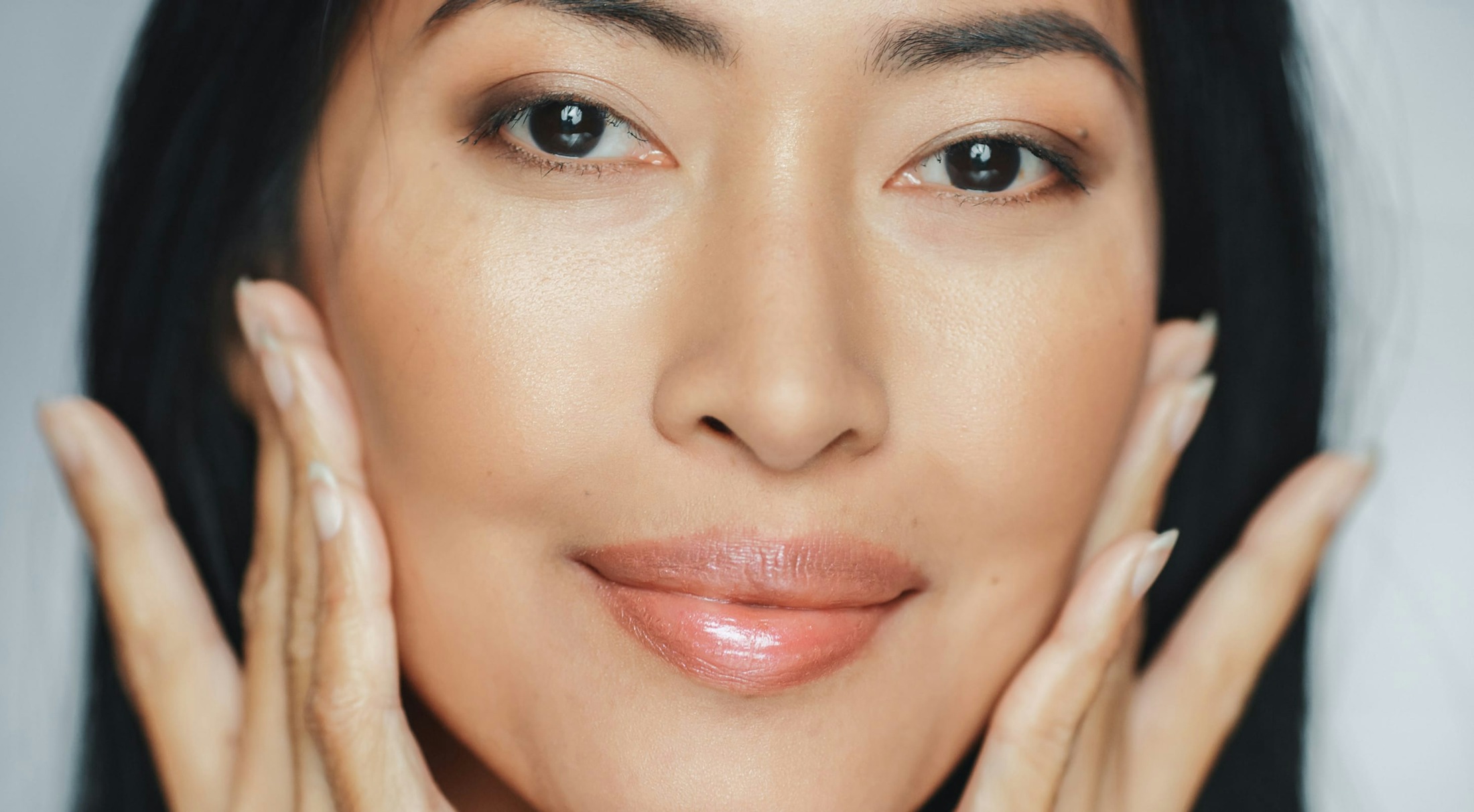 Close-up of a woman's face, with her fingers on her cheeks