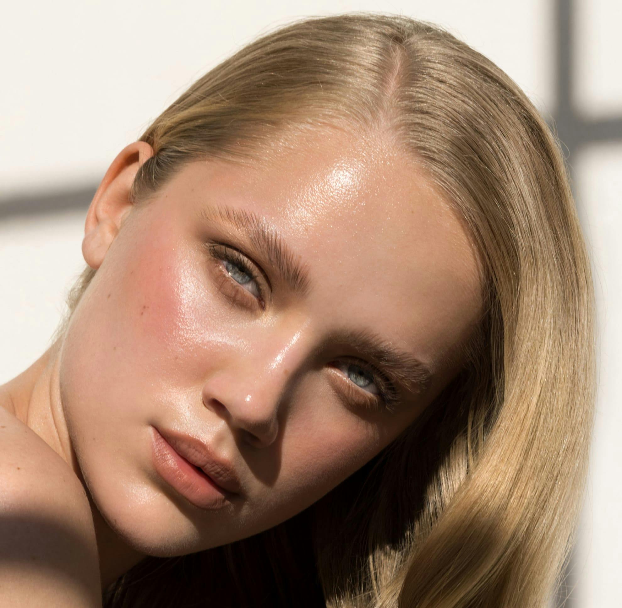 Woman with blond hair and makeup, head tilted
