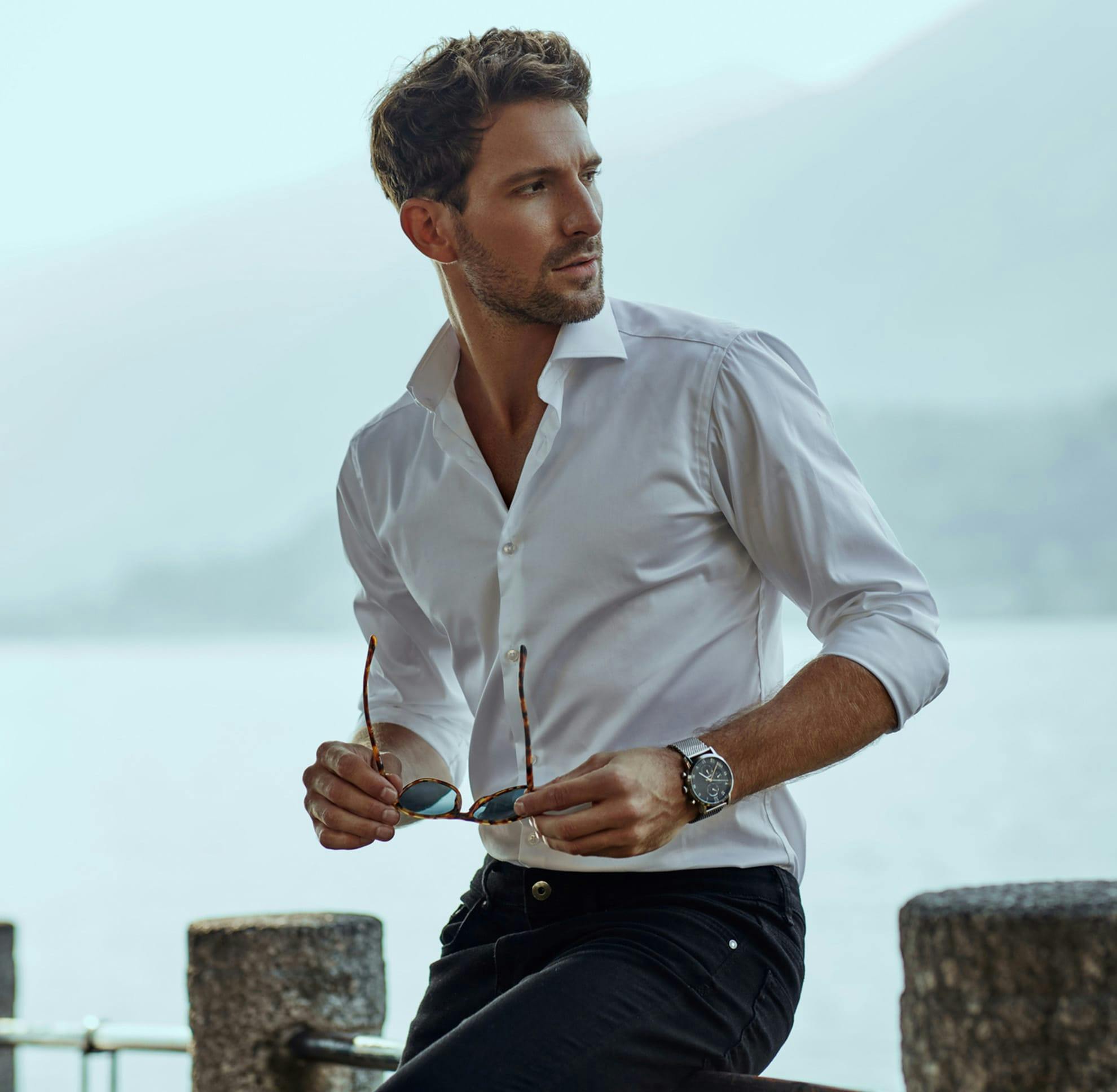 Man leaning against a railing with glasses in his hand