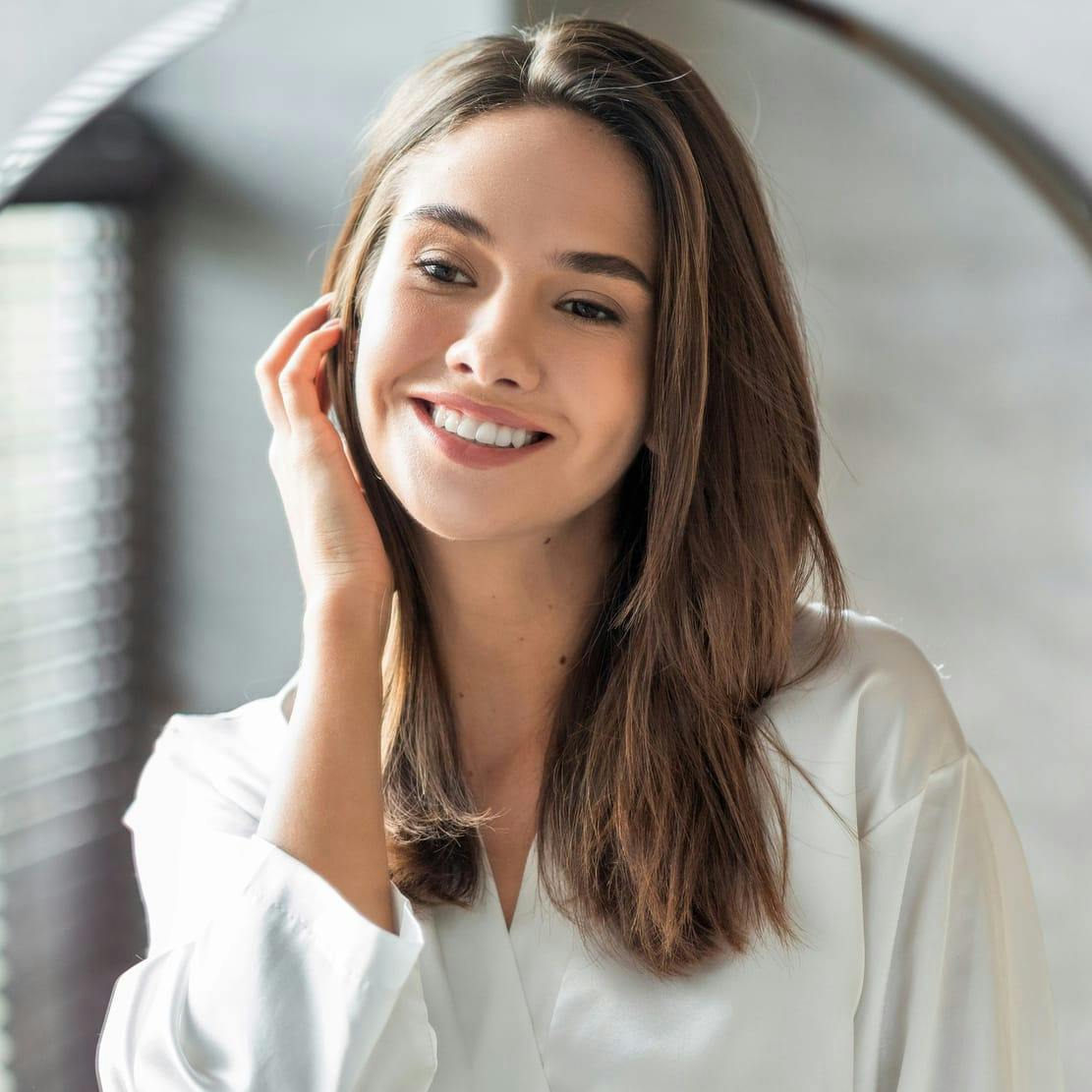 Woman looking in the mirror with a hand to her head