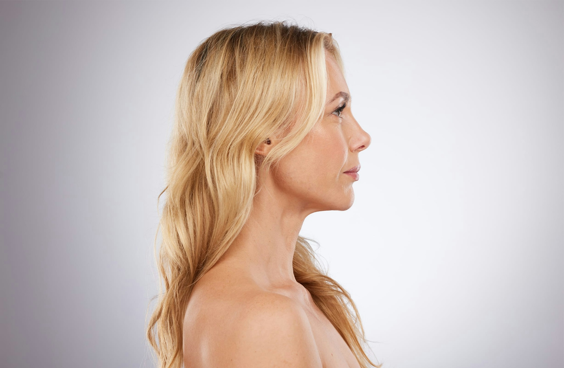 Woman with blond hair in front of a pink background