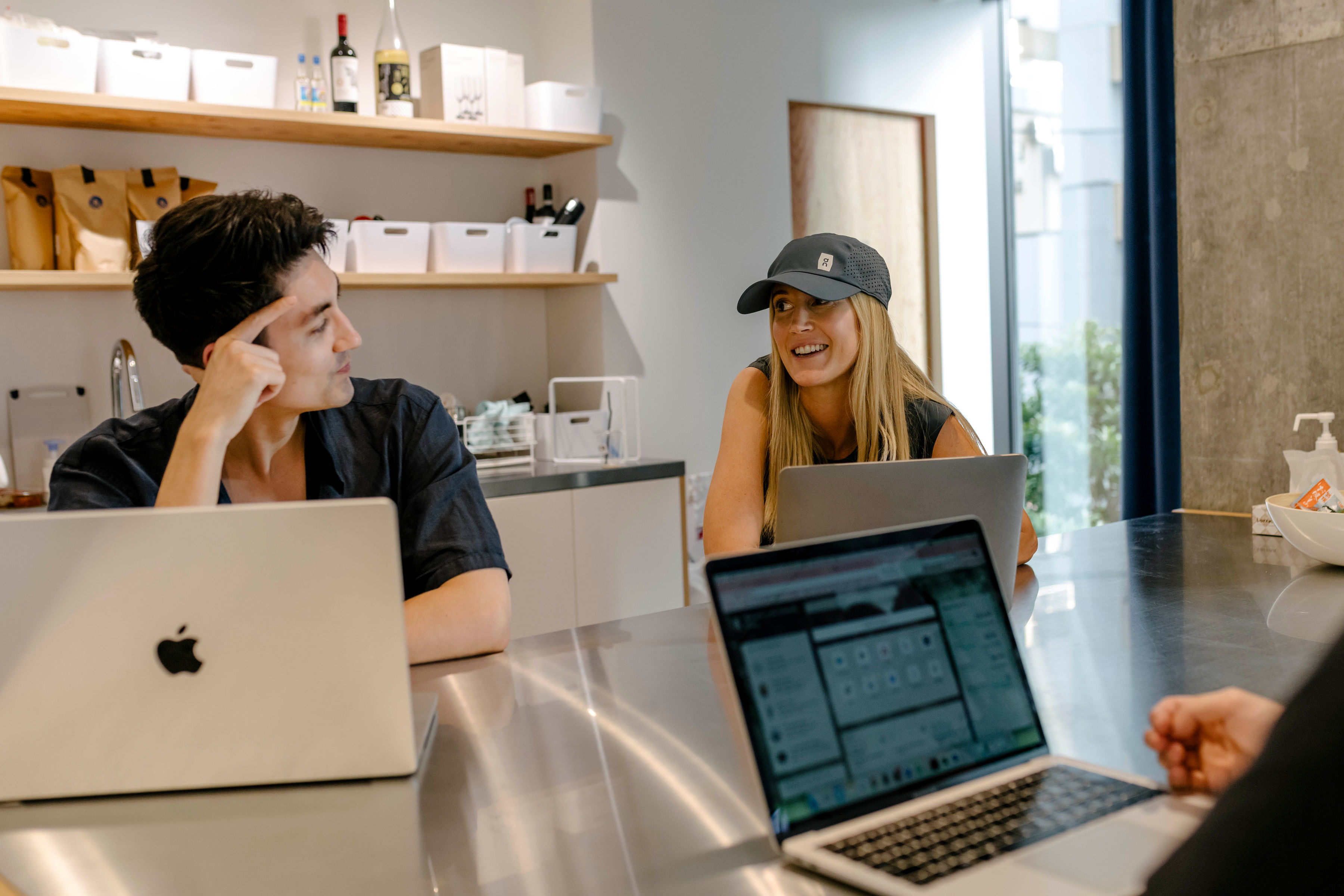 A woman wearing a cap chats to colleagues in a coffee shop