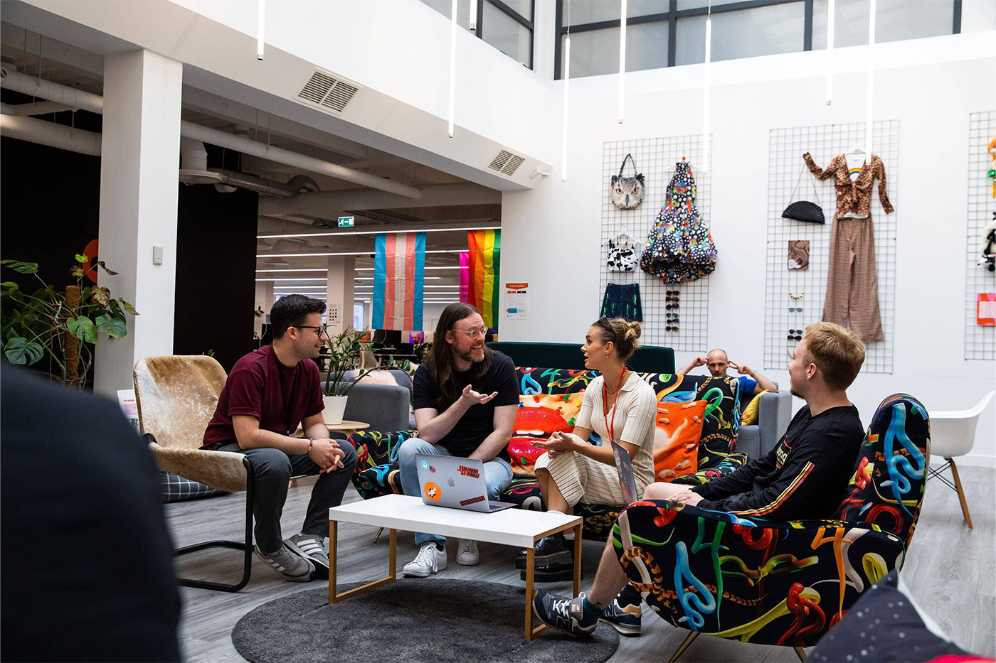 Four colleagues sit and chat in a vibrant, fashionable office