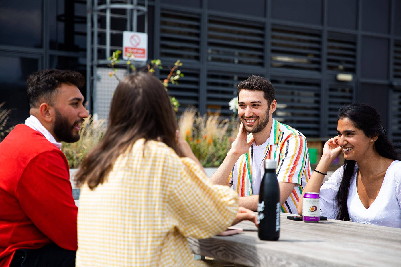 Four colleagues sitting outside talking over drinks