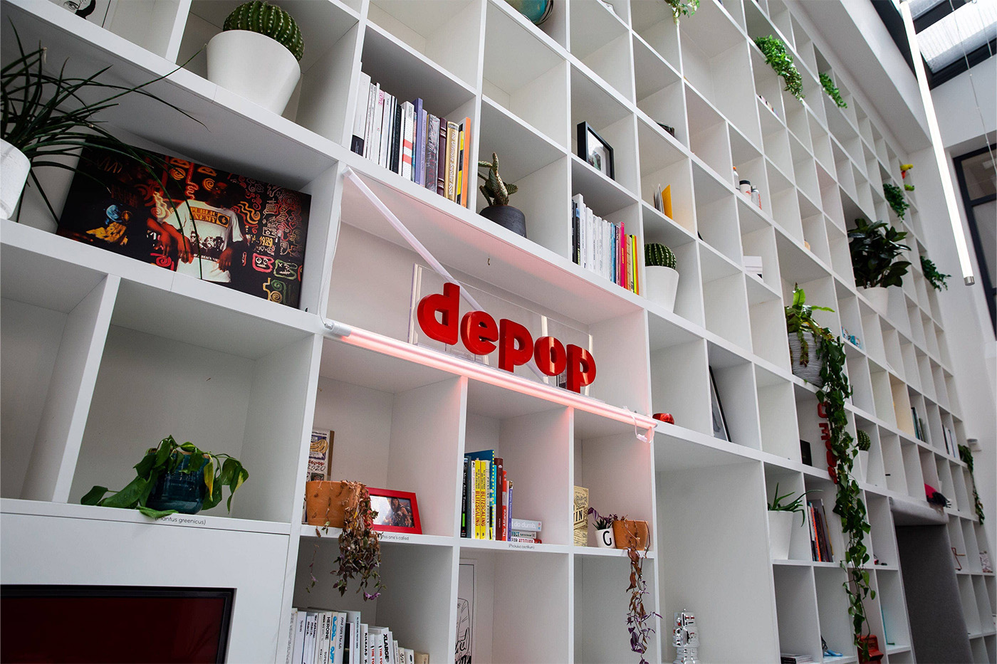 A bustling and unique shelving unit with a large 'depop' logo made from red plastic