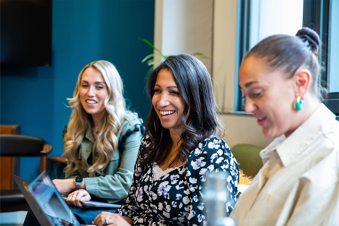 Three female colleagues smiling during a meeting