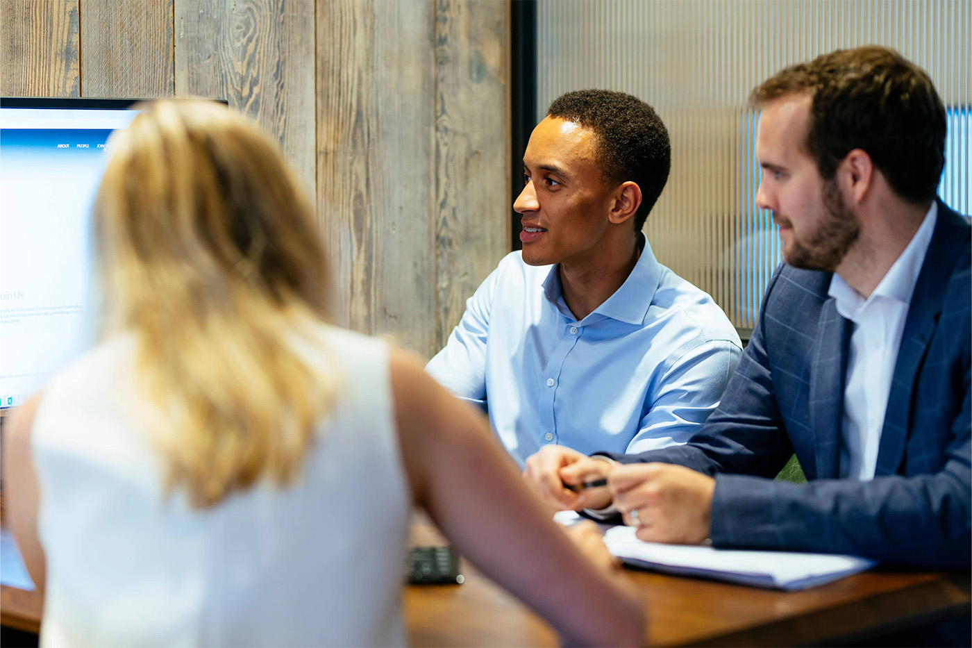 Three colleagues working together in a modern office with wood panelling