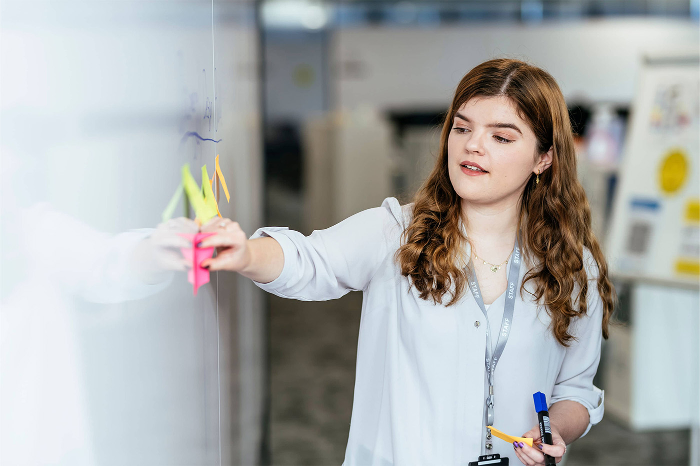 Woman at work displaying post-it notes on a whiteboard