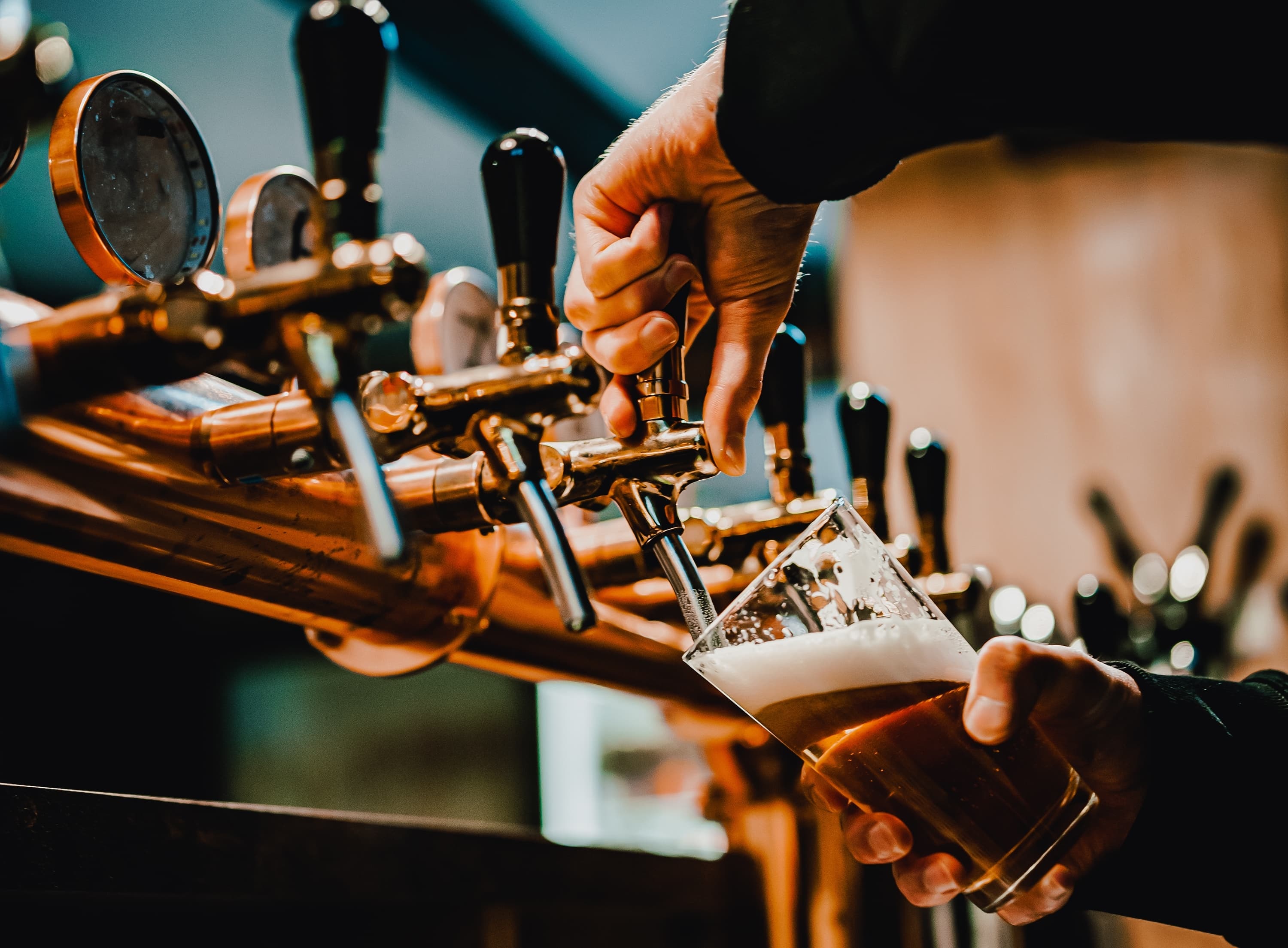 A hand pulling a pint of craft beer