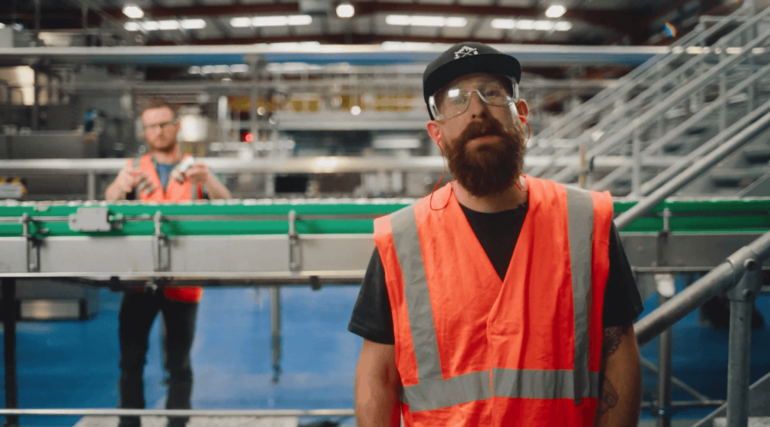 Two men wearing hi-vis inside a beer canning factory