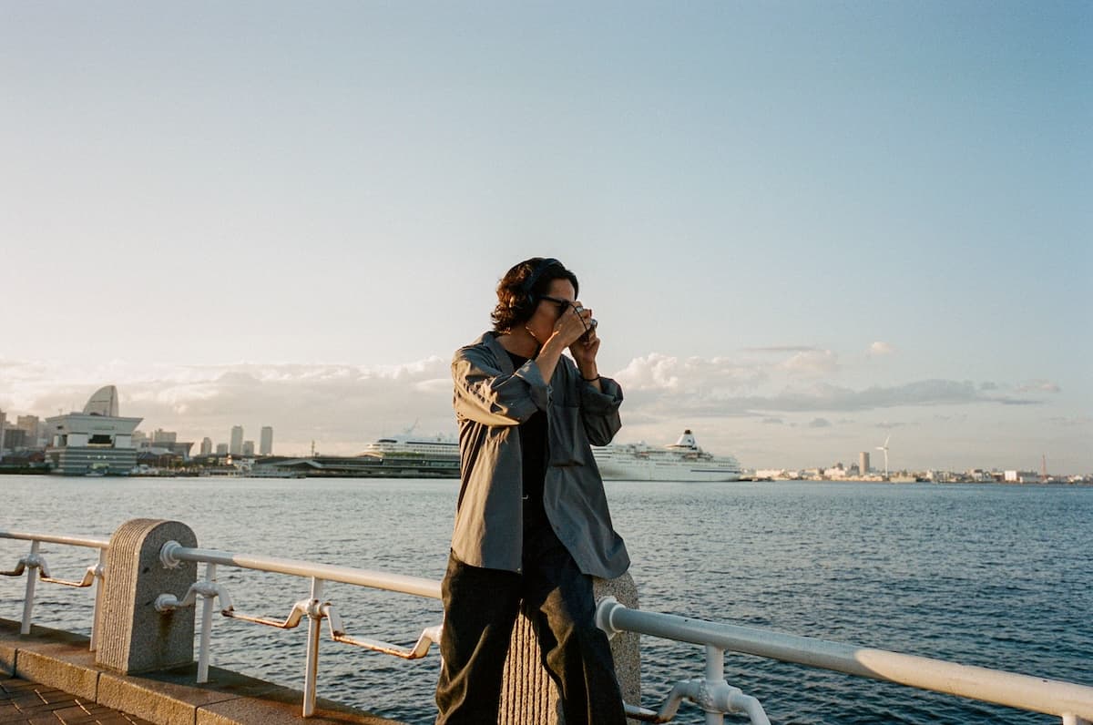 Film photograph of man taking a photograph on a pier, overlooking the sea