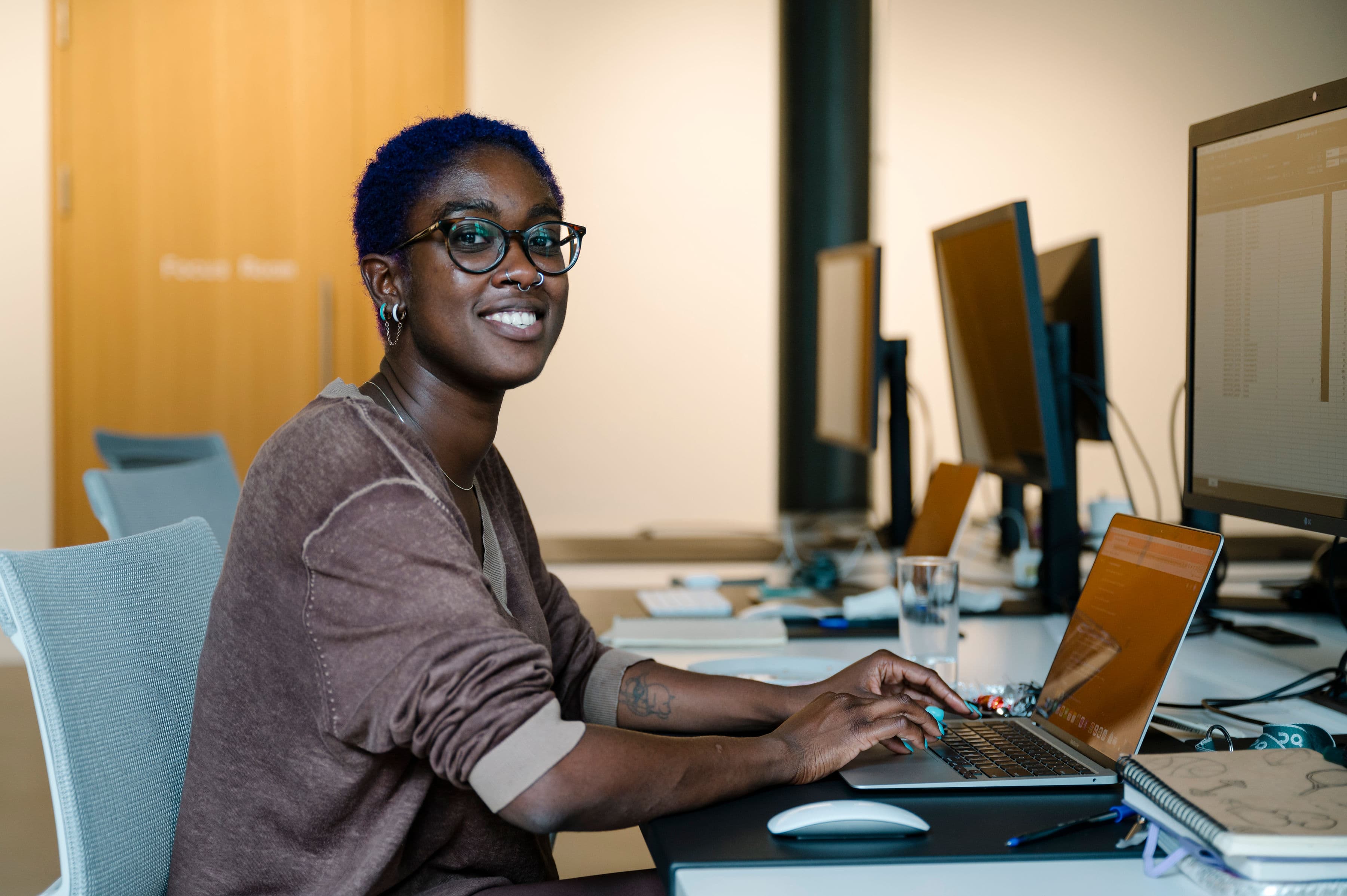 Woman smiling at the camera while working on her laptop