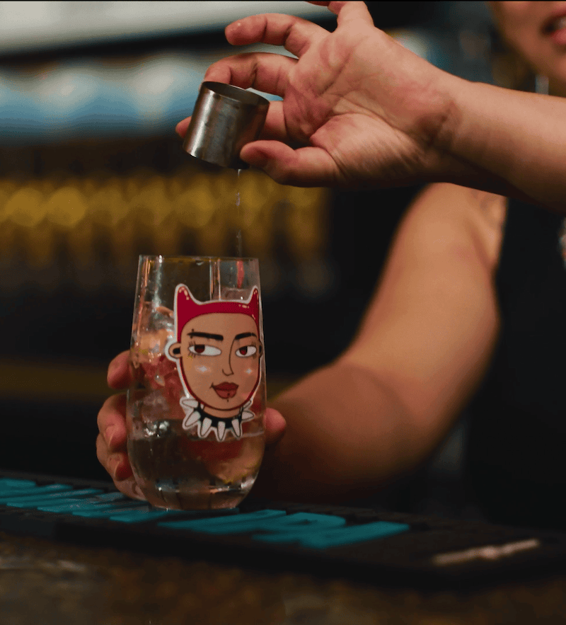 Hand pouring a shot of alcohol into an illustrated glass