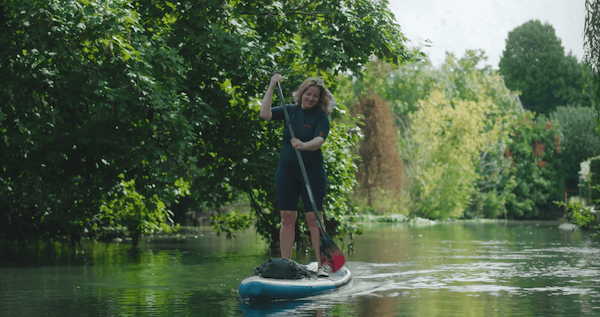 A video still of a woman paddleboarding