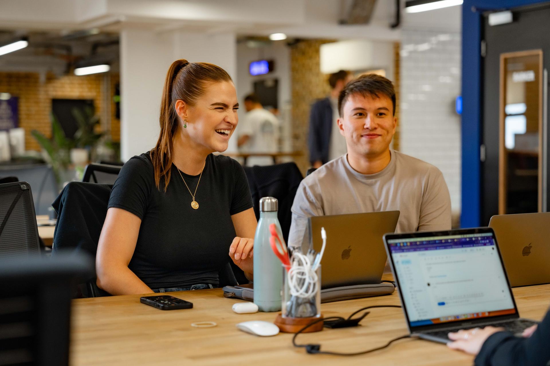 Two colleagues laughing together in bright modern office