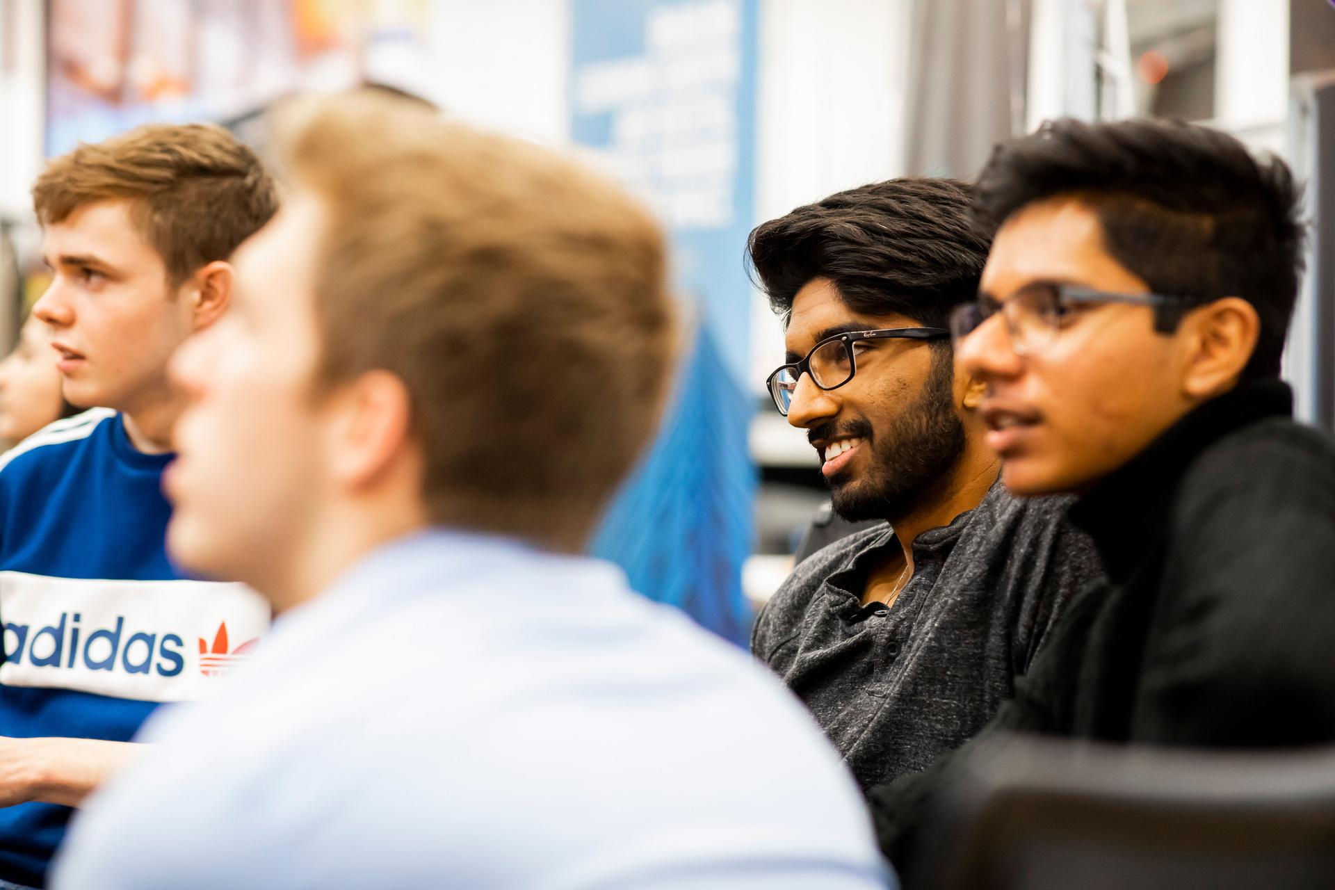 A diverse group of young men listen during a panel event