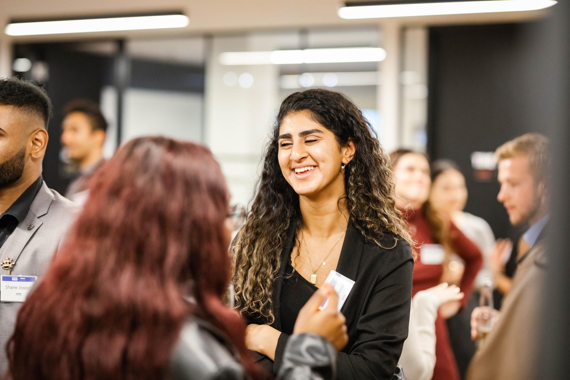 Student smiling and laughing while networking at a busy panel event