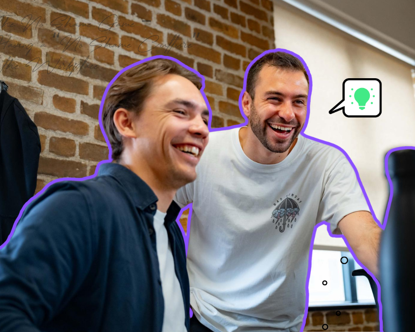 Male colleagues laughing at something on a computer screen in a bright modern office with brick walls