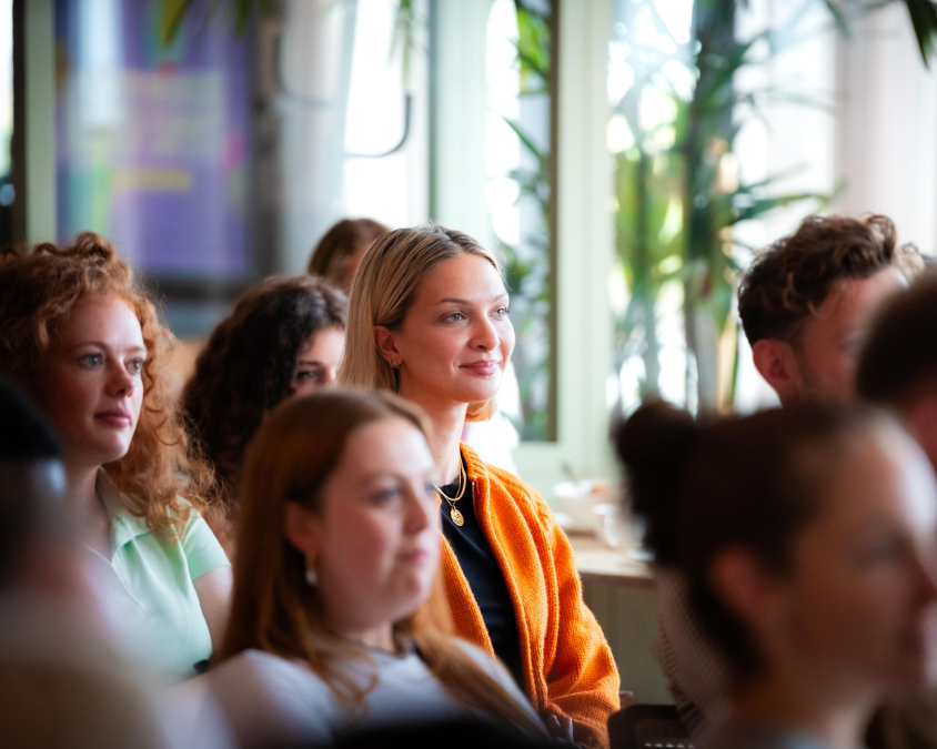 photo of blonde female in crowd watching a presentation