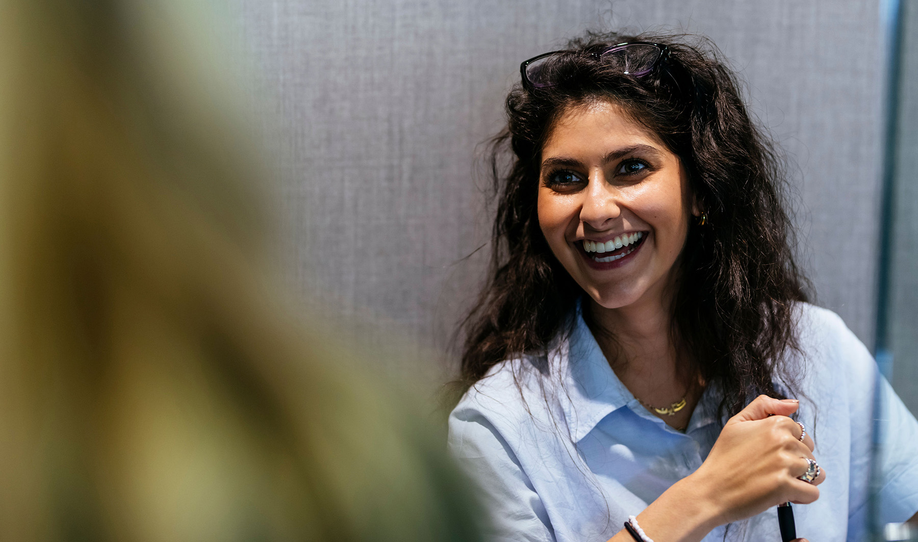 Smiling woman with curly hair laughing at colleague during a meeting