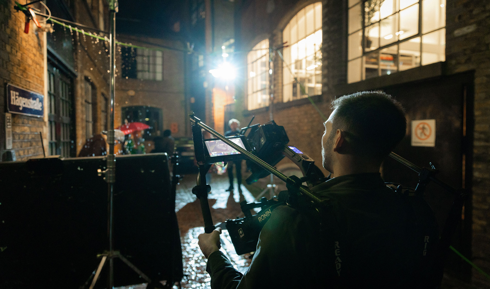 Image of production crew filming a video in the rain, actors carry umbrellas