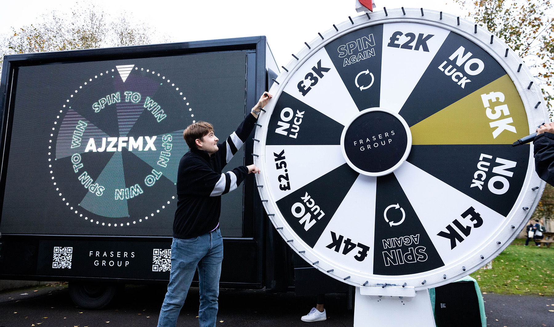 Photo of young student spinning a huge wheel full of prizes on campus