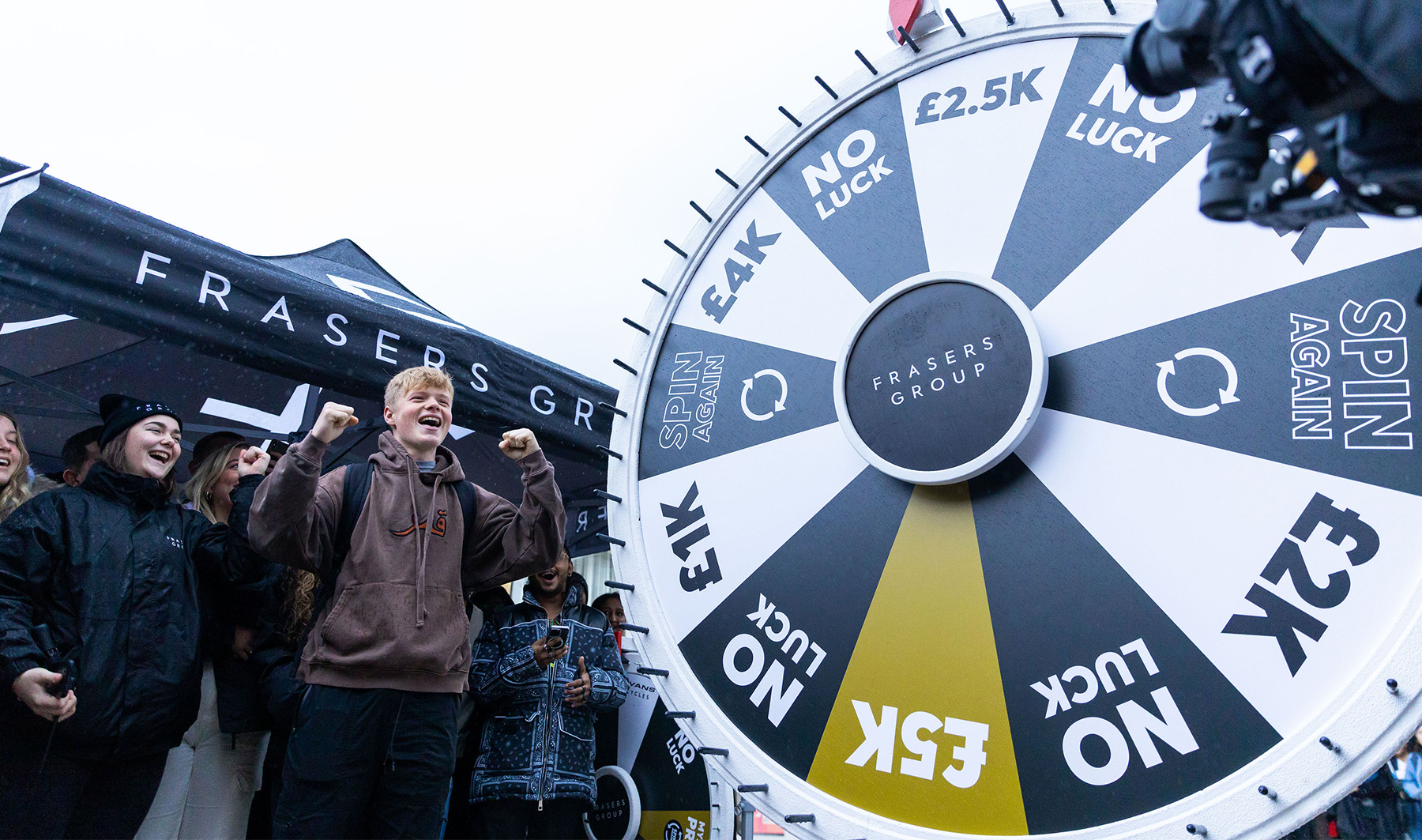 Photo of young male student winning a £2.5k prize in a spin the wheel competition