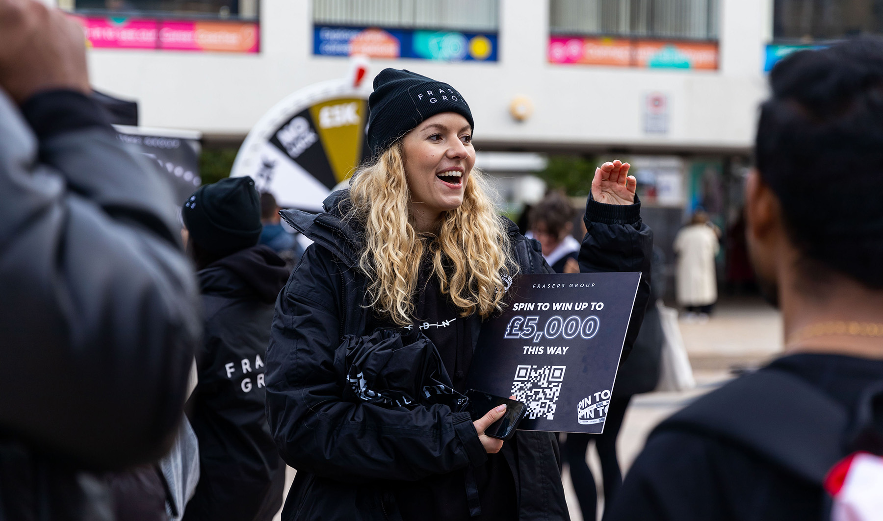 Photo of a blonde woman with curly hair promoting Frasers Group on campus