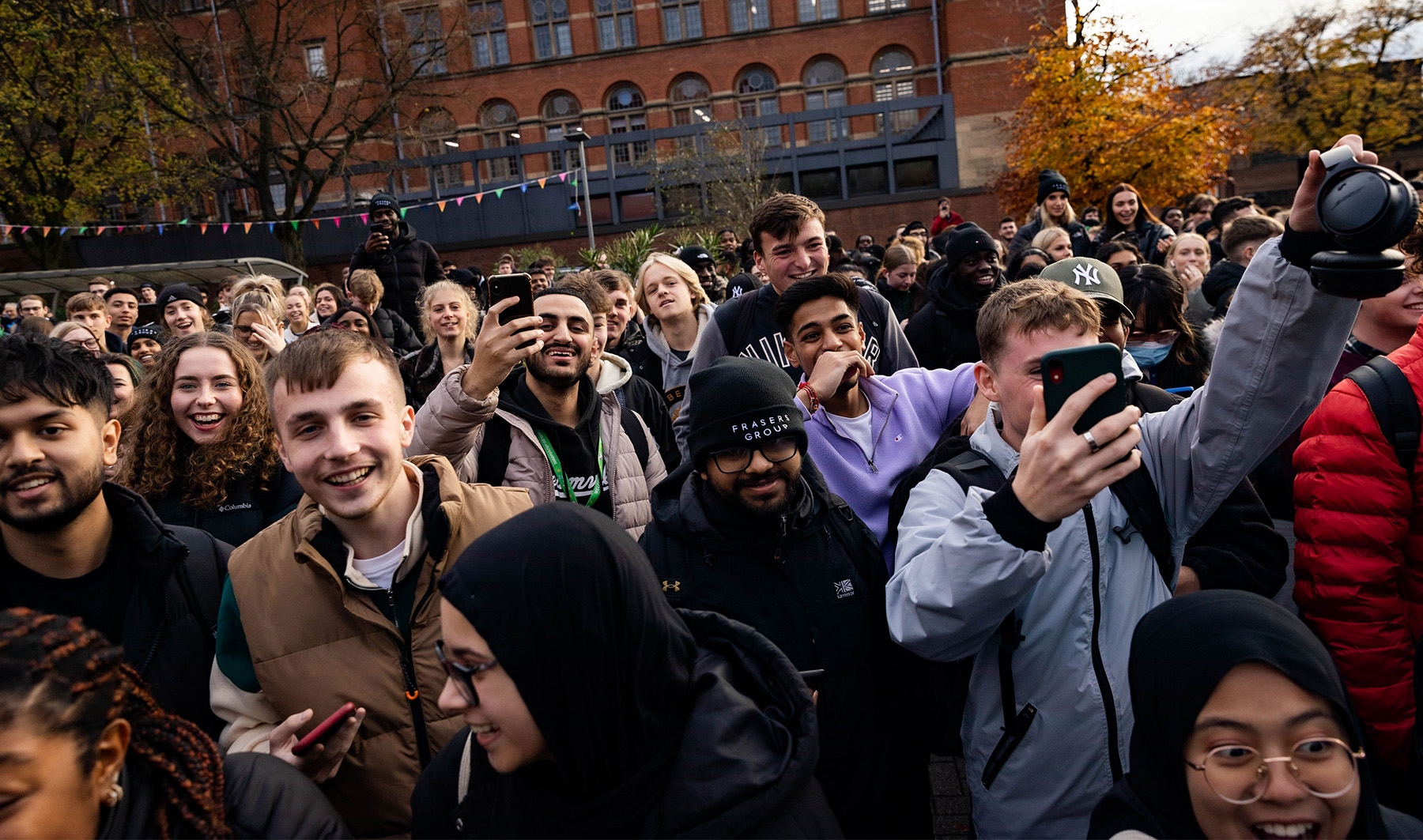 Crowd of students watching someone win a large cash prize. A few students are filming the event on their iPhones