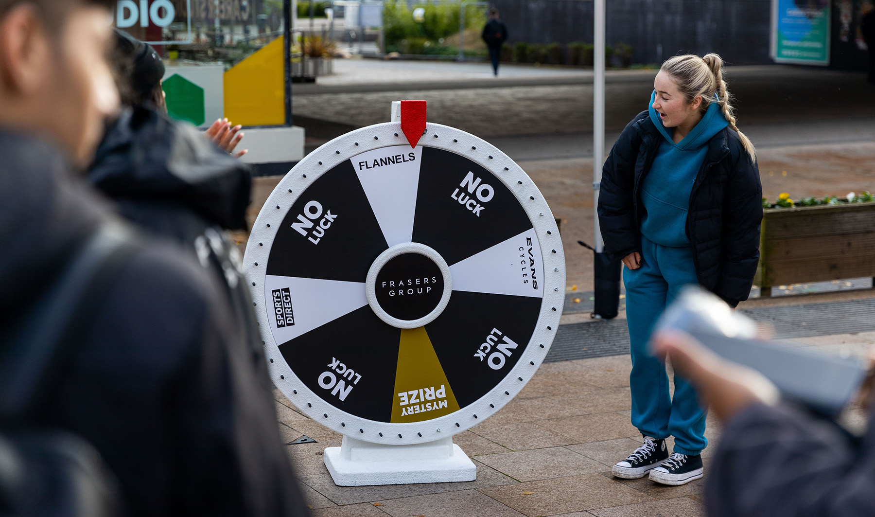 Female university student watching in shock as she spins the wheel