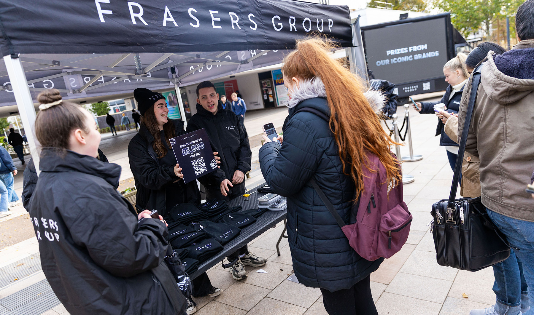 A student scanning the QR code at the Frasers Group stand