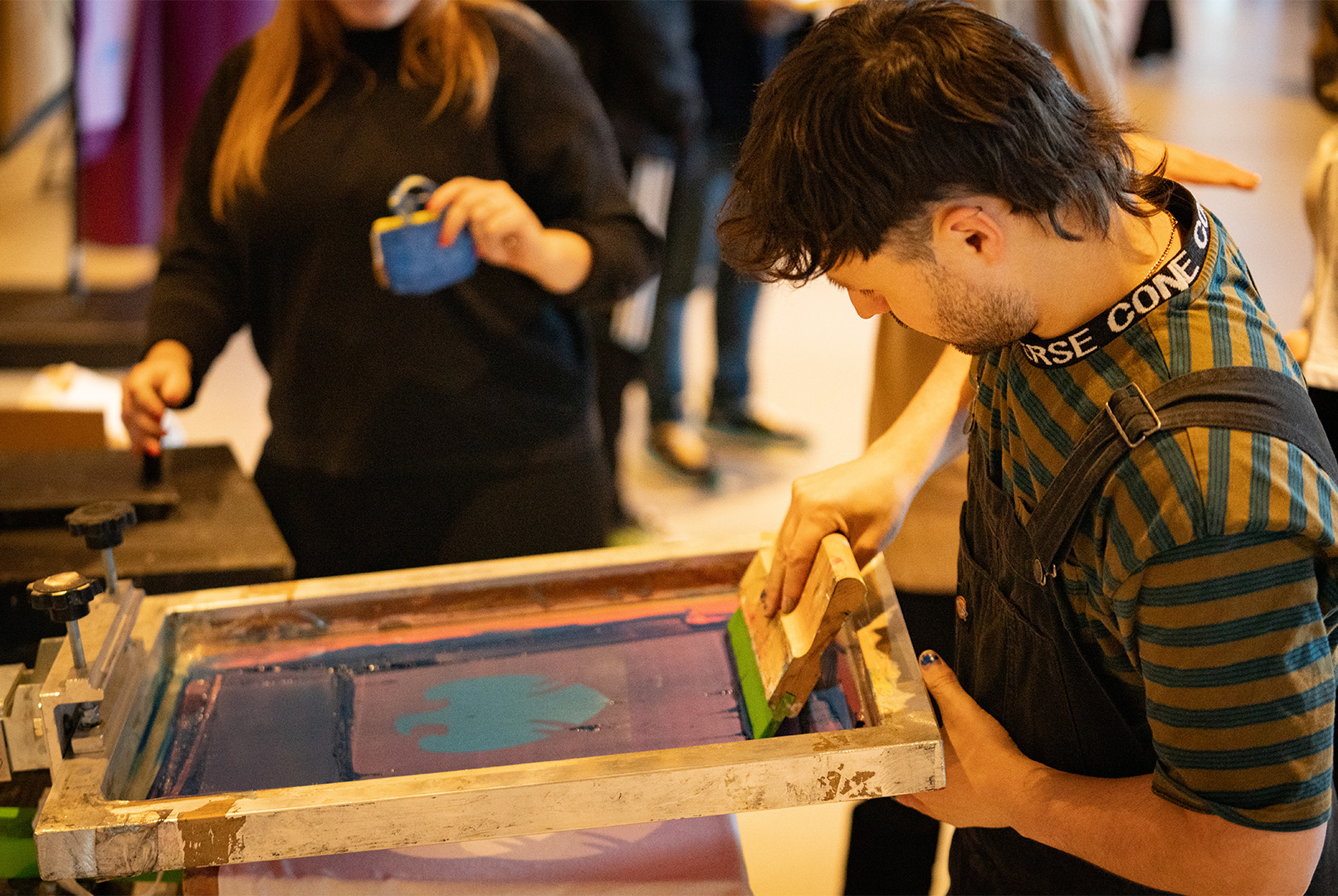 A male student screenprinting a tote bag during an event