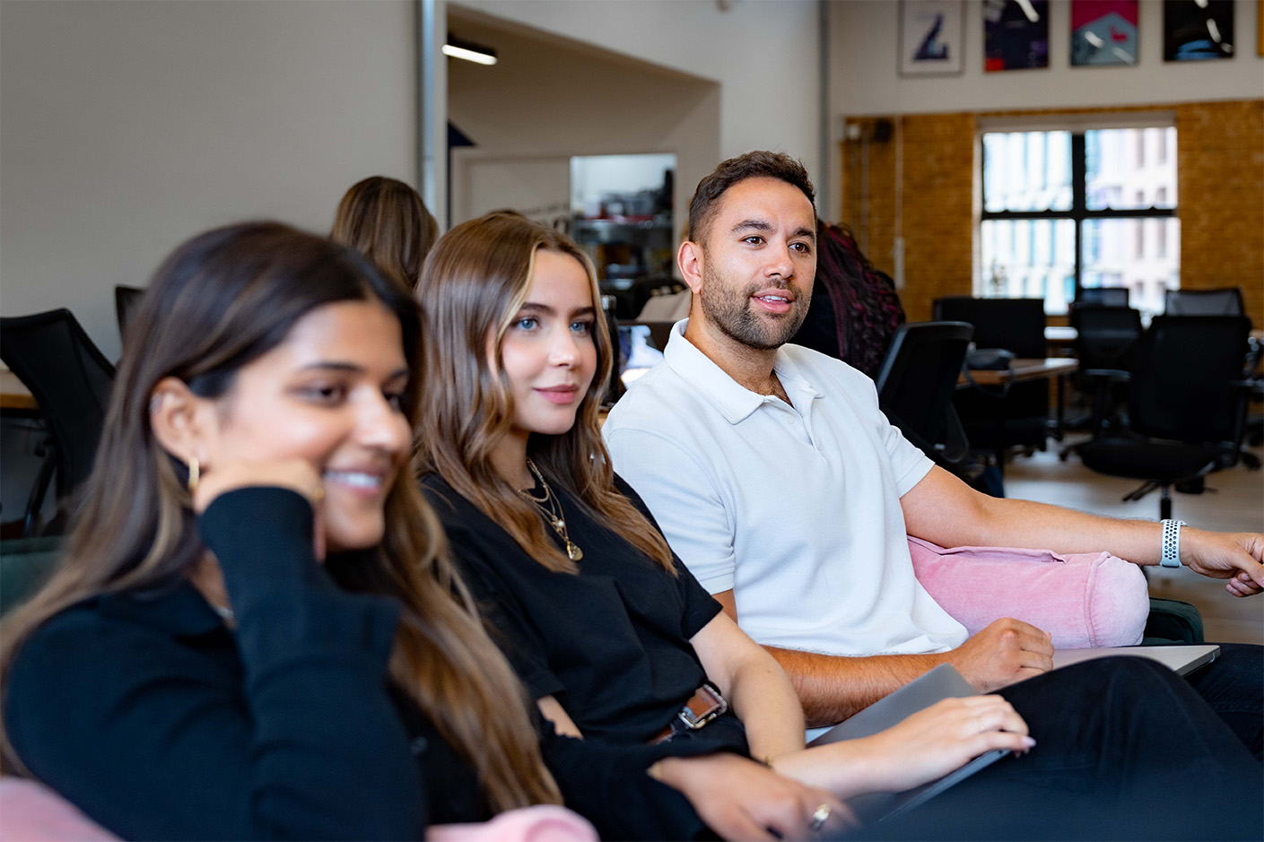 Three colleagues sat on a sofa listening during a meeting