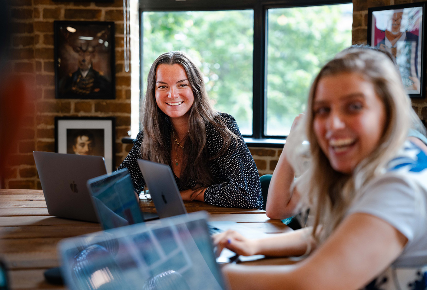 Image of a woman in a meeting, smiling with her laptop