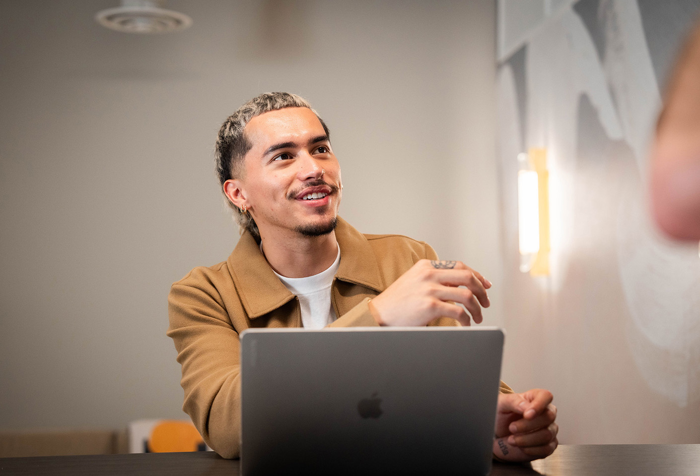 Image of young man contributing to a meeting, he's working on a laptop