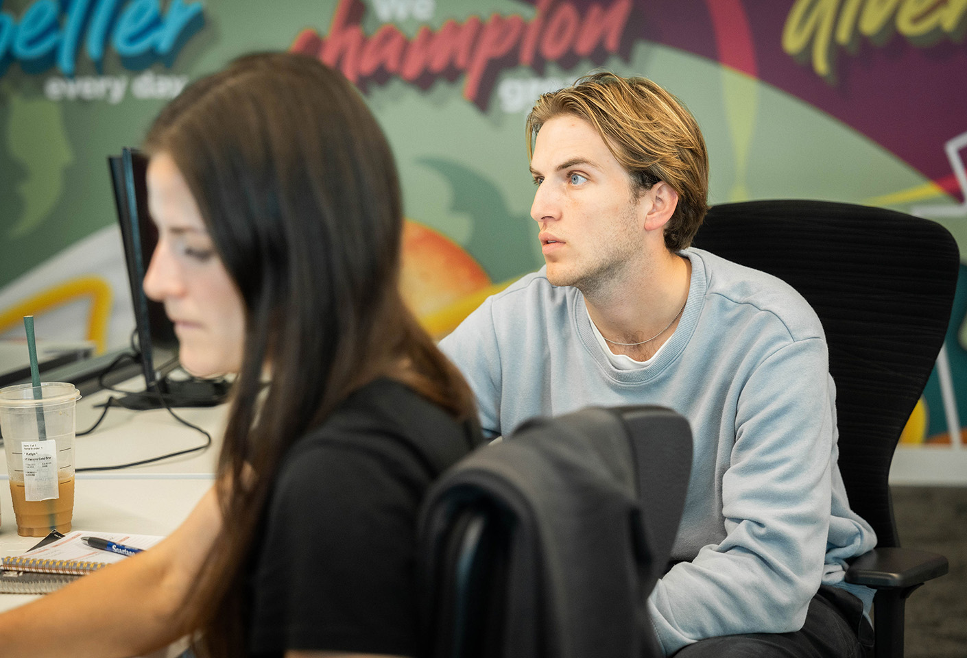 Image of man at a desk looking up at his colleague's screen