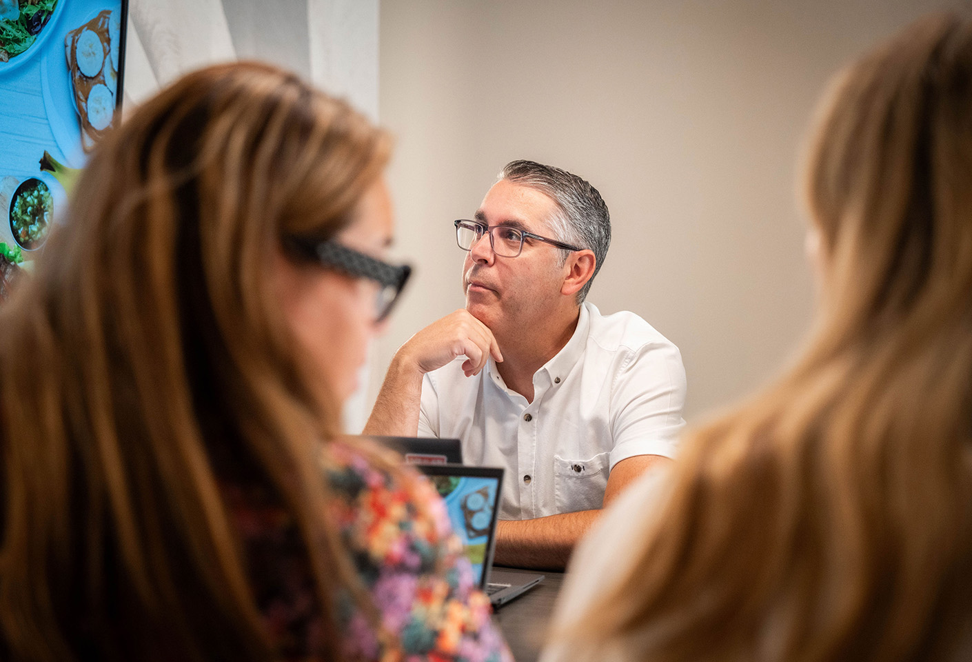 Image of older man wearing glasses and listening to a presentation