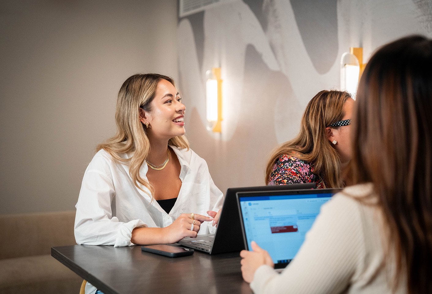 Image of young woman smiling up at somebody presenting during a meeting