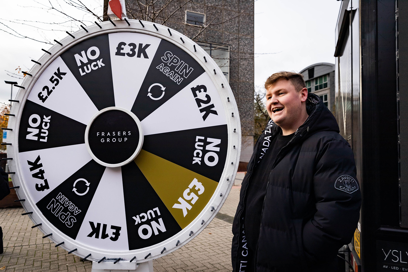 Image of male student with a large Frasers Group spinning wheel